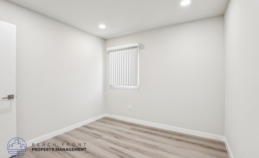 A room with a wooden floor and a window with blinds.